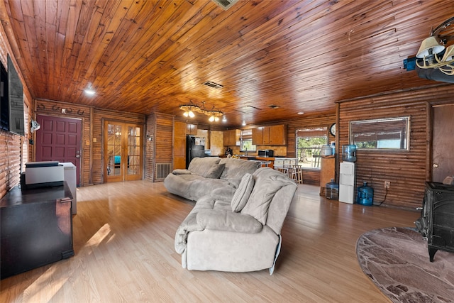 living room with a wood stove, wood walls, wooden ceiling, and light hardwood / wood-style flooring