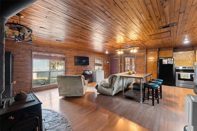 living room featuring vaulted ceiling, wood walls, light hardwood / wood-style floors, and wooden ceiling