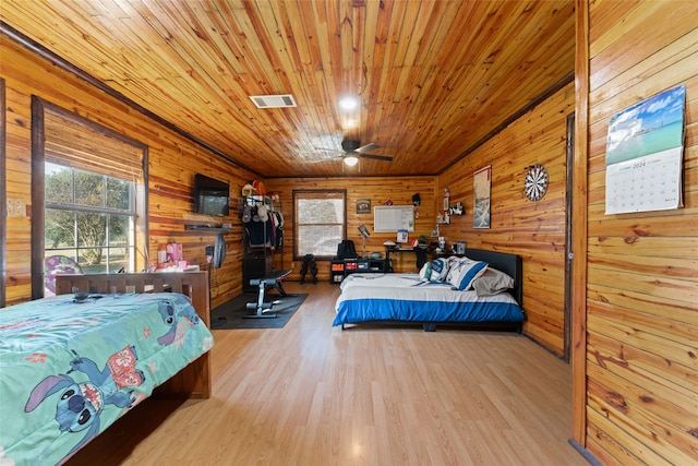 bedroom with wood ceiling, wood walls, and light hardwood / wood-style floors