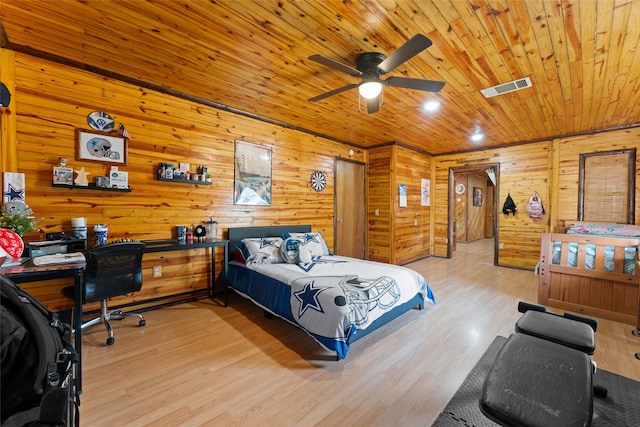 bedroom with wood walls, light hardwood / wood-style floors, and ceiling fan