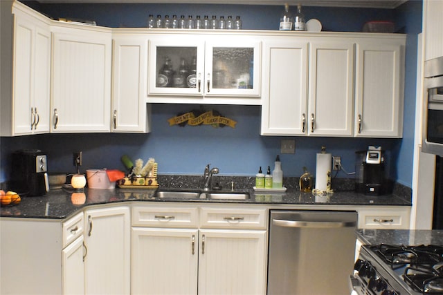 kitchen featuring white cabinets, stainless steel appliances, dark stone countertops, and sink