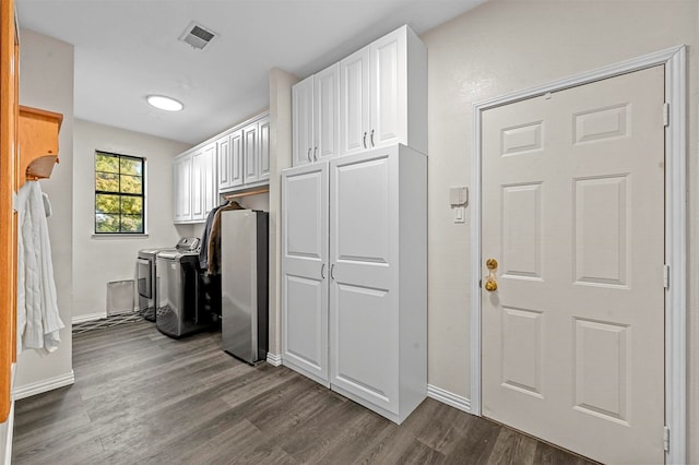 laundry area with dark wood-type flooring, cabinets, and washer and dryer