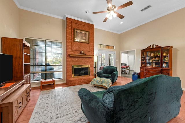 living room featuring a brick fireplace, ceiling fan, light hardwood / wood-style flooring, and crown molding