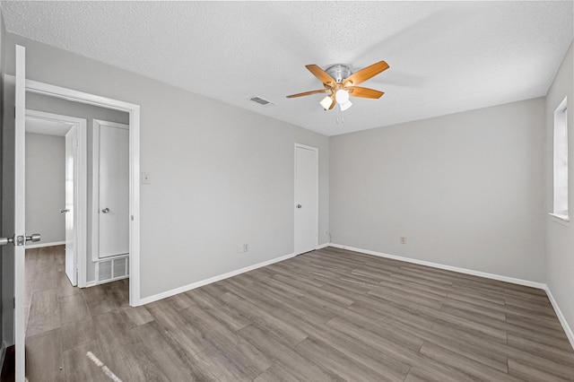 spare room featuring wood-type flooring, a textured ceiling, and ceiling fan