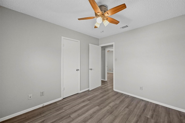 unfurnished bedroom featuring ceiling fan, wood-type flooring, and a textured ceiling