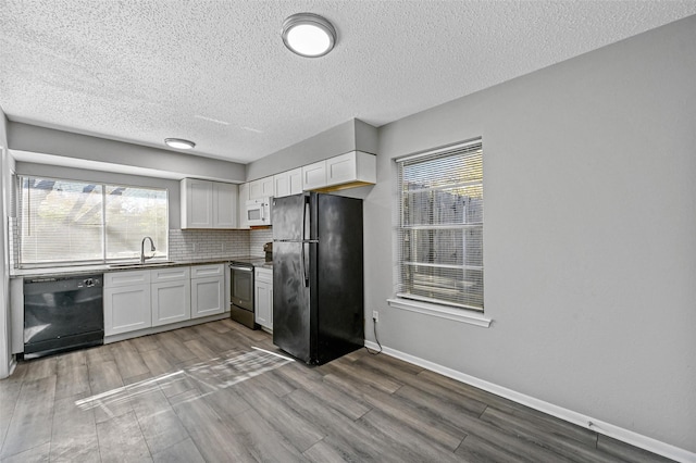 kitchen with tasteful backsplash, sink, white cabinets, hardwood / wood-style flooring, and black appliances