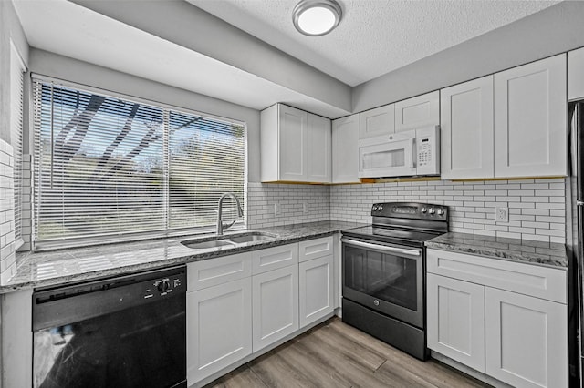 kitchen with stainless steel range with electric stovetop, sink, white cabinets, and black dishwasher