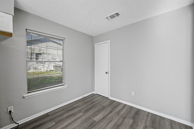 empty room featuring dark hardwood / wood-style flooring and a textured ceiling