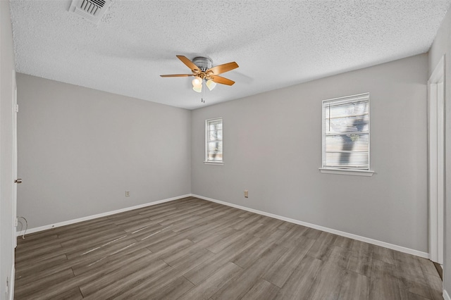 empty room with hardwood / wood-style floors, a textured ceiling, and ceiling fan