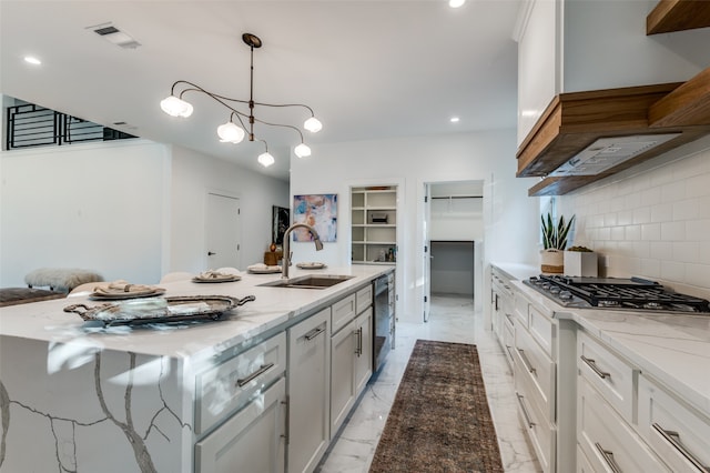 kitchen featuring sink, tasteful backsplash, a center island with sink, stainless steel appliances, and light stone countertops