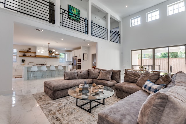 living room featuring a high ceiling, a notable chandelier, and a healthy amount of sunlight