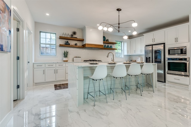 kitchen featuring appliances with stainless steel finishes, a breakfast bar, a chandelier, and white cabinetry