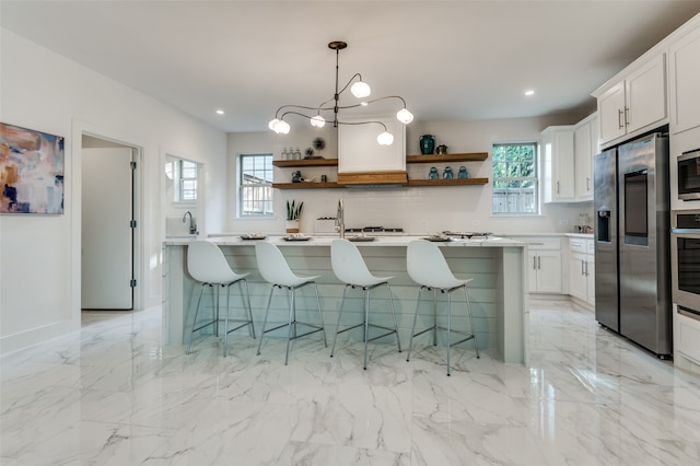 kitchen with appliances with stainless steel finishes, a healthy amount of sunlight, and white cabinetry