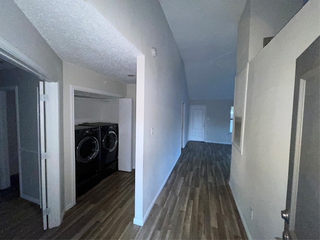 corridor featuring a textured ceiling, dark hardwood / wood-style floors, vaulted ceiling, and washing machine and clothes dryer