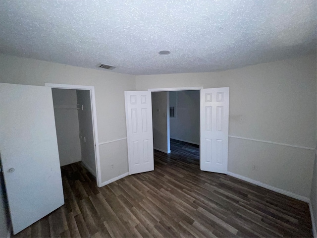 unfurnished bedroom with a textured ceiling, a closet, and dark hardwood / wood-style flooring