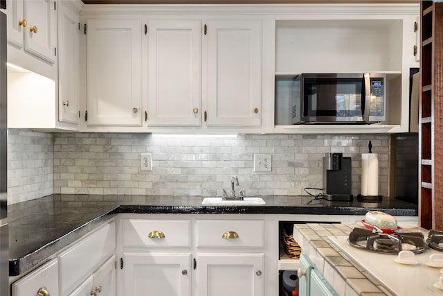 kitchen with white cabinetry, decorative backsplash, and sink