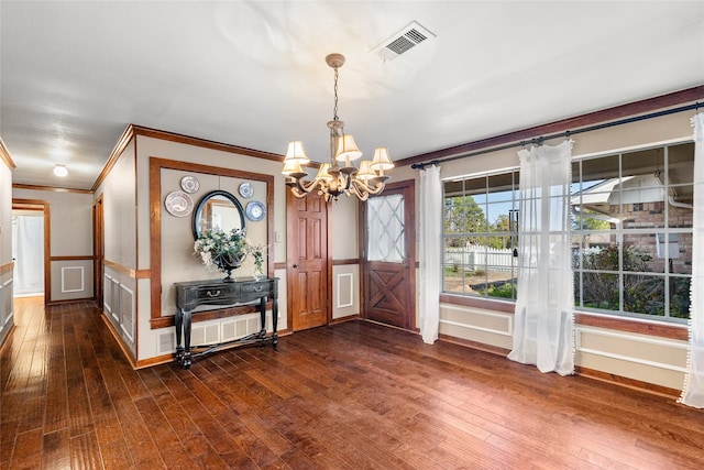 entrance foyer with dark wood-type flooring, crown molding, and a notable chandelier