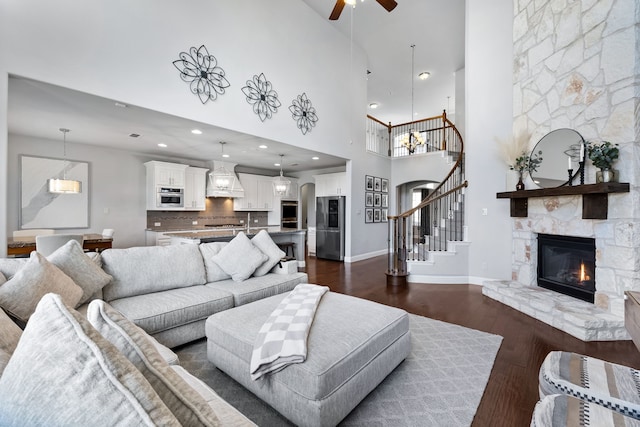 living room featuring a fireplace, a high ceiling, dark hardwood / wood-style floors, and ceiling fan