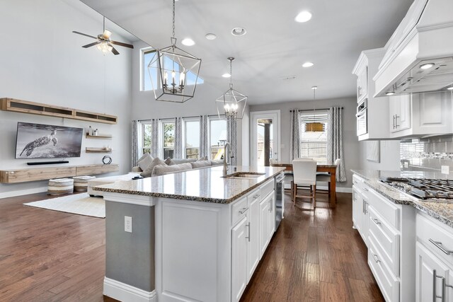 kitchen with a center island with sink, a healthy amount of sunlight, white cabinets, and custom range hood