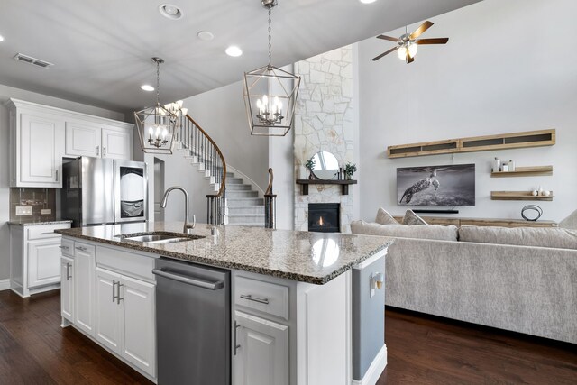 kitchen with a center island with sink, white cabinets, sink, dark hardwood / wood-style floors, and a fireplace