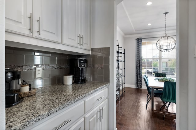 kitchen with tasteful backsplash, crown molding, dark wood-type flooring, pendant lighting, and white cabinets