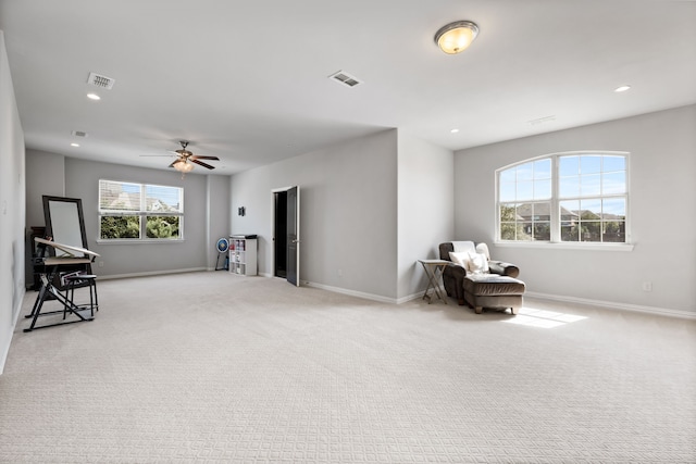 living area with light colored carpet, plenty of natural light, and ceiling fan