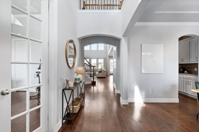 entryway with dark wood-type flooring, a high ceiling, and ornamental molding