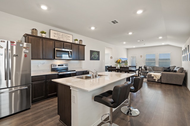 kitchen with a breakfast bar area, dark hardwood / wood-style floors, sink, stainless steel appliances, and an island with sink