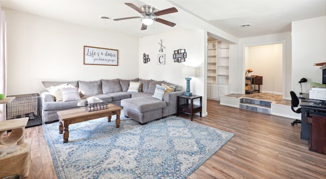 living room featuring hardwood / wood-style floors, built in features, and ceiling fan