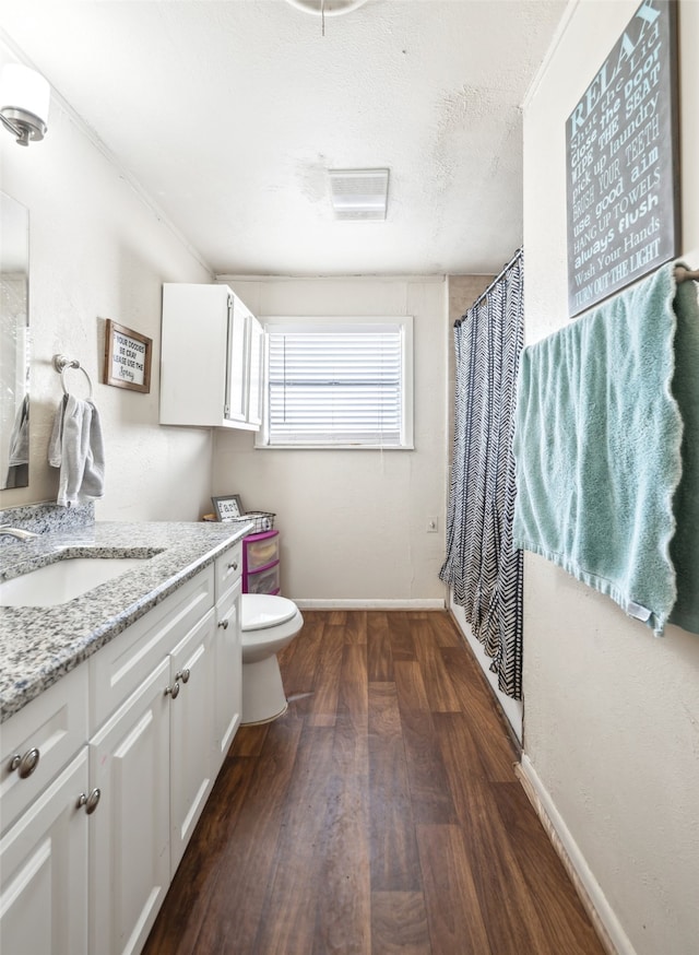 bathroom with a textured ceiling, wood-type flooring, toilet, vanity, and a shower with shower curtain