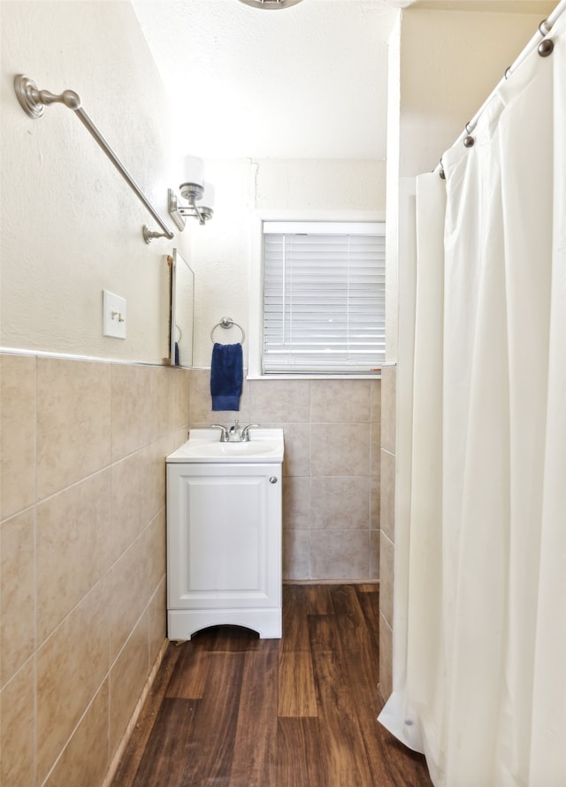 bathroom featuring vanity, walk in shower, wood-type flooring, and tile walls