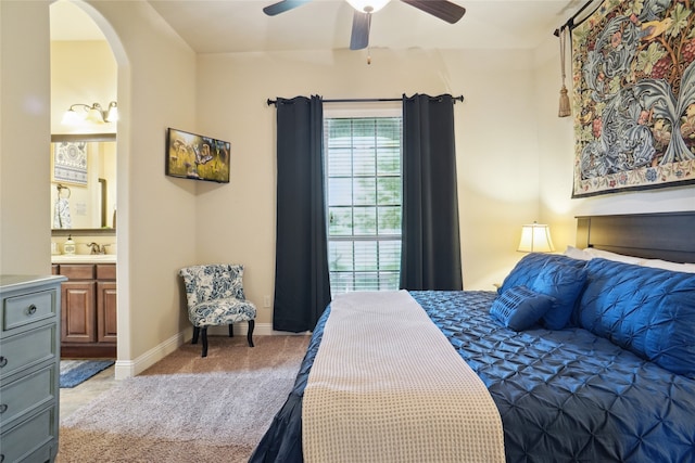 bedroom featuring ceiling fan, light colored carpet, and ensuite bath