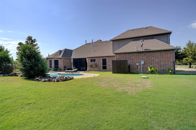 back of property with a fenced in pool, a patio, and a lawn