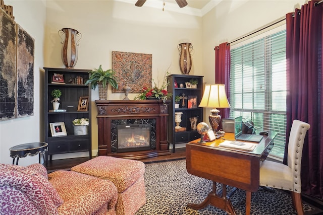 office space featuring ceiling fan, wood-type flooring, ornamental molding, and a high end fireplace