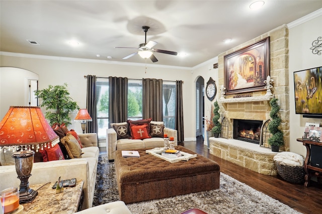 living room with ceiling fan, a fireplace, crown molding, and dark wood-type flooring