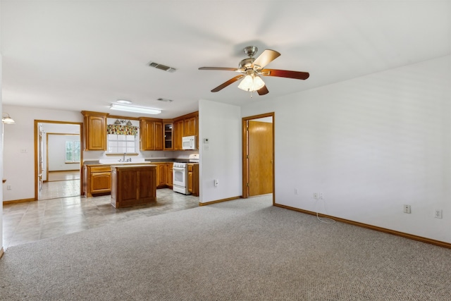 kitchen with ceiling fan, a center island, light carpet, white appliances, and sink