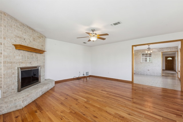 unfurnished living room with a fireplace, ceiling fan, and hardwood / wood-style floors