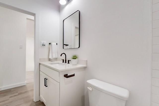 bathroom with wood-type flooring, toilet, and vanity