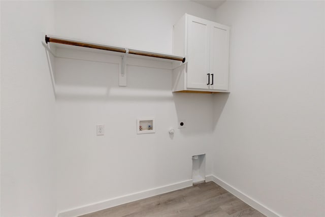 laundry area featuring gas dryer hookup, hookup for an electric dryer, light wood-type flooring, hookup for a washing machine, and cabinets