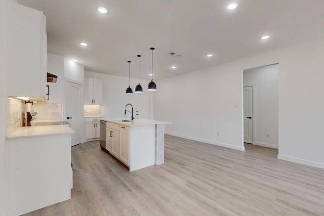 kitchen featuring a center island with sink, range, hanging light fixtures, sink, and white cabinets