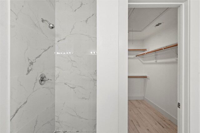 bathroom with hardwood / wood-style flooring and tiled shower