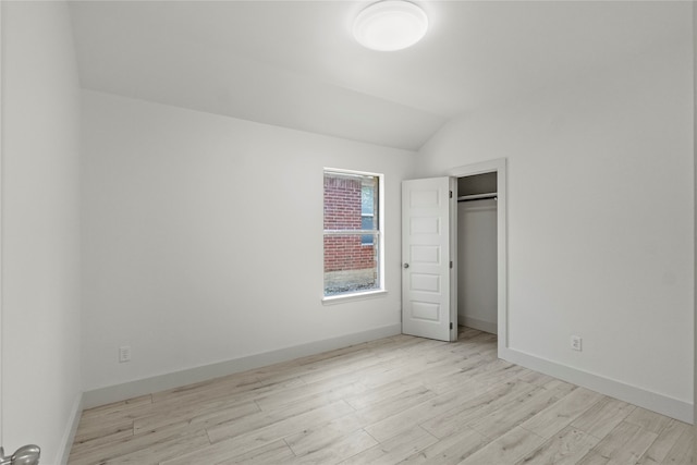 unfurnished bedroom featuring a closet, vaulted ceiling, and light wood-type flooring