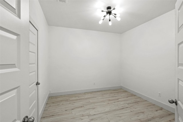 spare room featuring an inviting chandelier and light hardwood / wood-style floors