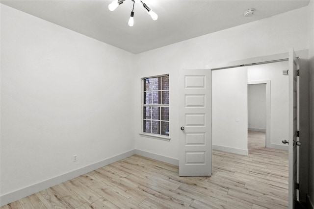 spare room with a chandelier and light hardwood / wood-style flooring