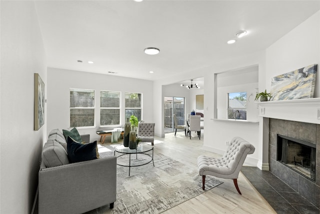 living room featuring a healthy amount of sunlight, a fireplace, hardwood / wood-style floors, and a chandelier