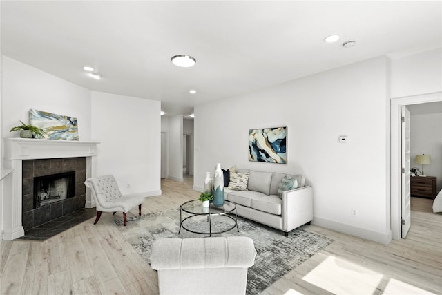 living room with a tile fireplace and light hardwood / wood-style floors