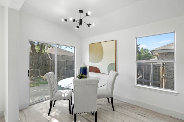 dining space featuring light wood-type flooring, plenty of natural light, vaulted ceiling, and an inviting chandelier