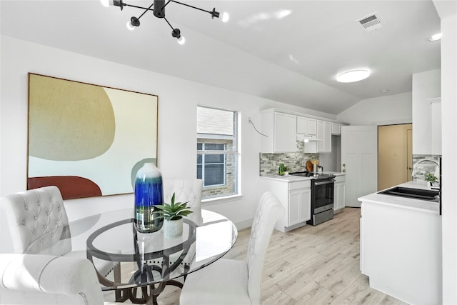 dining room with vaulted ceiling, sink, and light wood-type flooring