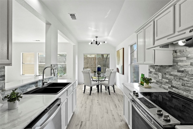 kitchen with stainless steel appliances, sink, extractor fan, vaulted ceiling, and light hardwood / wood-style flooring