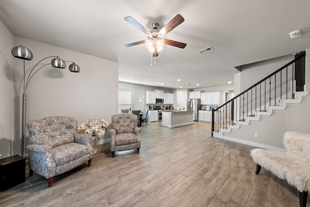 living room featuring ceiling fan and light hardwood / wood-style floors